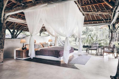 a bedroom with a canopy bed and a table and chairs at Batukaru Coffee Estate in Tabanan