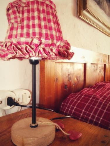 a lamp on top of a wooden table with a bed at Baita Casera Caviazza in Falcade