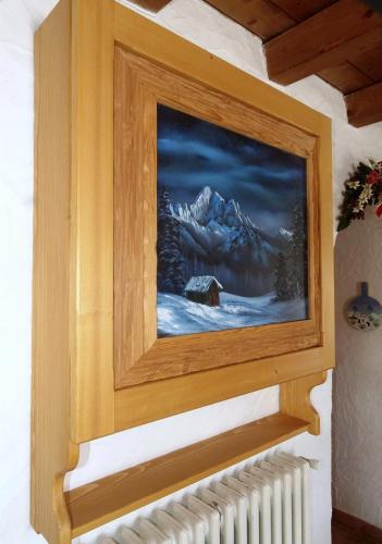 a painting of a winter scene on a wall with a radiator at Baita Casera Caviazza in Falcade