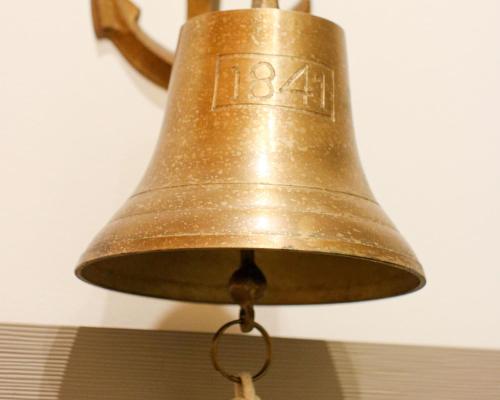 a large bronze bell hanging from a ceiling at Regina Maris by Baltic Home in Świnoujście