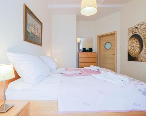 a bedroom with a white bed with pink clothes on it at Regina Maris by Baltic Home in Świnoujście