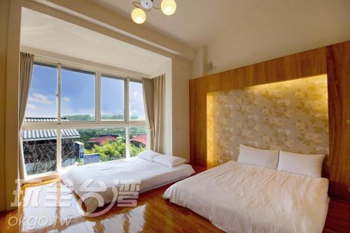 a bedroom with two beds and a large window at Miaoli Sanyi Shantongyazhu Homestay in Sanyi