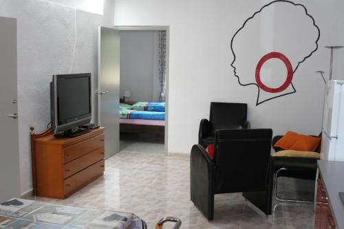 a living room with a tv and a chair and a bedroom at Appartement Deltebre minimo 2 Noches in Deltebre