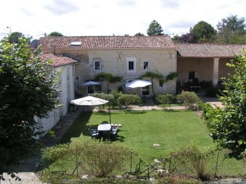 a garden with two tables and umbrellas in front of a house at Gite Andromeda - Les Constellations in Doeuil-sur-le-Mignon