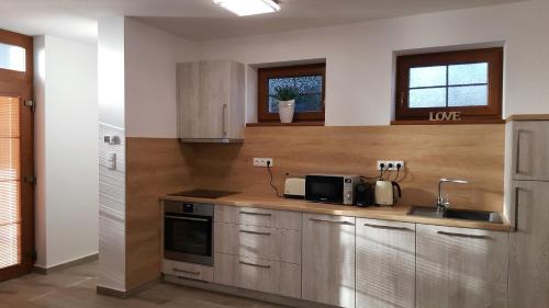 a kitchen with wooden cabinets and a sink and a microwave at Village Romantic Apartments by Český Krumlov - adults only in Střížov