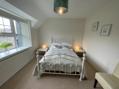 - une chambre avec un lit blanc, 2 tables et une fenêtre dans l'établissement Creamery Cottage, à Kenmare
