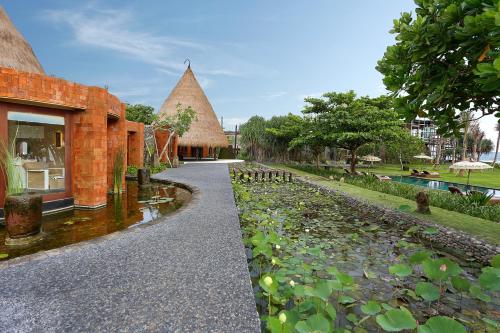 a walkway next to a building with a pond at WakaGangga in Tabanan
