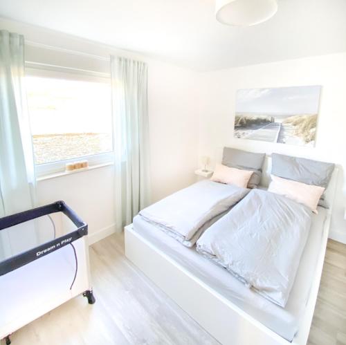a white bedroom with a bed and a window at Frieda´s Ostseetraum in Börgerende-Rethwisch