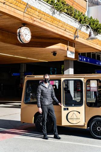 a man wearing a mask standing in front of a van at The Christiania Mountain & Spa Resort in Zermatt