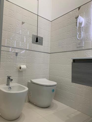 a white bathroom with a toilet and a sink at B&B Vittorio Emanuele in Licata