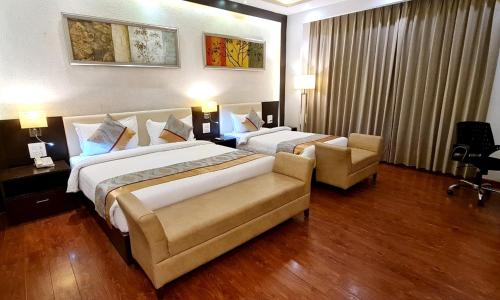 a hotel room with two beds and a couch at Bravura Gold Resort in Meerut