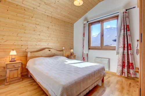 une chambre avec un lit et une grande fenêtre dans l'établissement Les Césaries A7, à Morzine