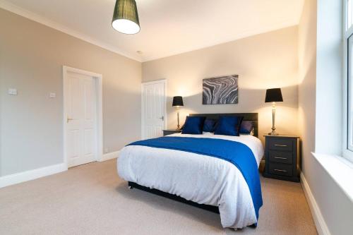 a bedroom with a large bed with blue pillows at Modern Living 2 Bedroom Apartment South Wilmslow in Wilmslow