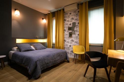 a bedroom with a bed and a desk and a chair at Boutique Hôtel Azur in Marseille