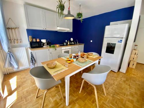- une cuisine avec une table en bois et des chaises blanches dans l'établissement Cosy Flat 2V6, à Saint-Étienne