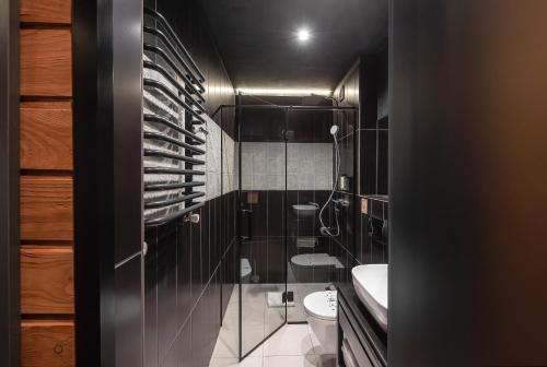 a black bathroom with a toilet and a sink at Stara Pravda Hotel - Vykrutasy in Bukovel
