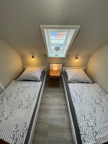 2 Betten in einem kleinen Zimmer mit Dachfenster in der Unterkunft Haus Corinna in Büsum