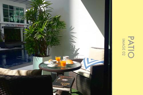 卡馬拉海灘的住宿－Pool Access 2 BDR Stylish Condo，天井上的桌子和两杯橙汁