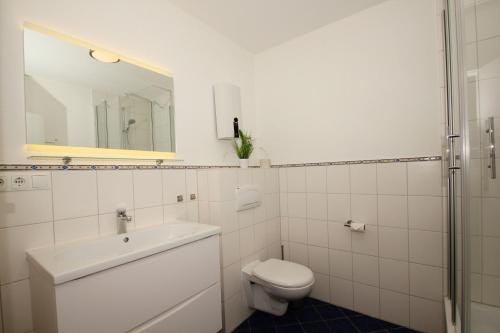 bagno con servizi igienici, lavandino e specchio di Ferienresidenz Kap Arkona FeWo12 - Terrasse a Putgarten