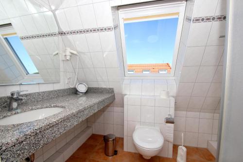 a bathroom with a sink and a toilet and a window at Hafenhäuser Wiek FeWo 06 - Balkon, Meerblick in Wiek auf Rügen 