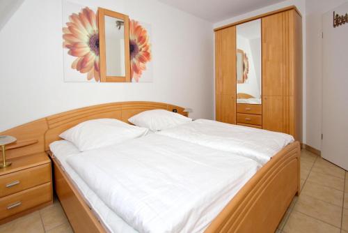 a bedroom with a large bed with white sheets at Hafenhäuser Wiek FeWo 15 - Balkon, Meerblick in Wiek auf Rügen 