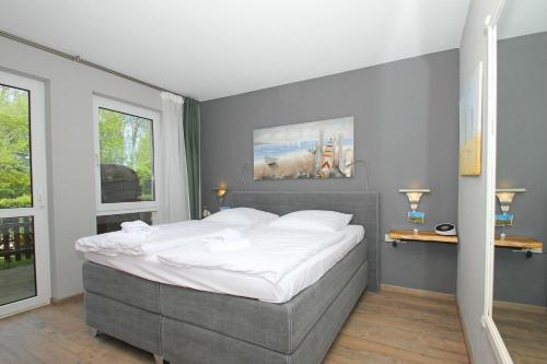 1 dormitorio con 1 cama grande con sábanas blancas en strandnah mit Terrasse, gratis Nutzung vom AHOI Erlebnisbad und Sauna in Sellin - Strandhaus Mönchgut FeWo09, en Lobbe