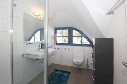 a white bathroom with a sink and a toilet at Ferienhaus Stranddistel Haus - Terrasse, Garten, Sauna in Klein Gelm