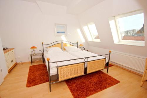 a bedroom with a bed and two rugs at Hafenhäuser Wiek FeWo 11 - Balkon, Meerblick in Wiek auf Rügen