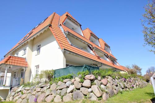a white house with an orange roof and a rock wall at Hafenhäuser Breege FeWo 13 - Terrasse, Meerblick in Breege