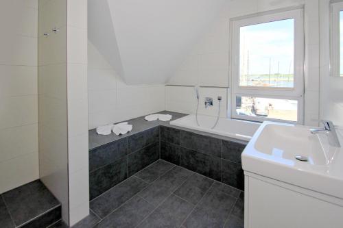 Baño blanco con bañera y lavamanos en hafennahes Ferienhaus mit Terrasse und Meerblick - Ferienhaus TimpeTe Steuerbord, en Gager