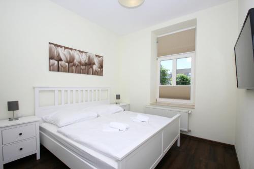 ein weißes Schlafzimmer mit einem weißen Bett und einem Fenster in der Unterkunft Ferienwohnung mit eigener Sauna in zentraler Lage - Kurhaus Nordstrand FeWo 32 in Göhren
