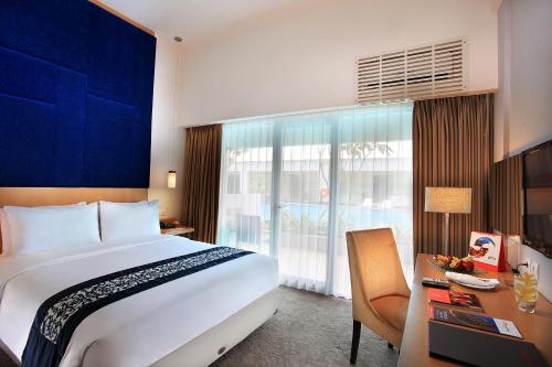 a hotel room with a large bed and a desk and a window at Swiss-Belinn Malang in Malang