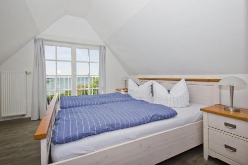 a bedroom with a bed with a blue comforter and a window at strandnahe Idylle am Meer, private Badestelle, Strandkorb - Gutshof Ostseeblick in Neuendorf