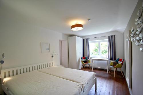 ein Schlafzimmer mit einem Bett und zwei Stühlen und einem Fenster in der Unterkunft märchenhafte Villa in idyllischer Lage und mit Meerblick - Villa Hermine in Altefähr