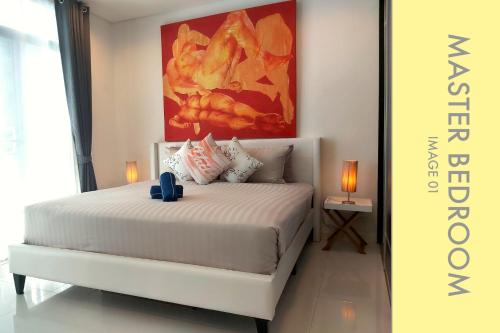 a bedroom with a white bed with a painting on the wall at Pool Access 2 BDR Stylish Condo in Kamala Beach