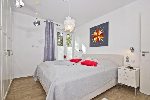 een witte slaapkamer met een wit bed met rode kussens bij hafennahe Ferienwohnung im Erdgeschoss mit Terrasse - Haus Hafenkieker FeWo 02 in Lauterbach