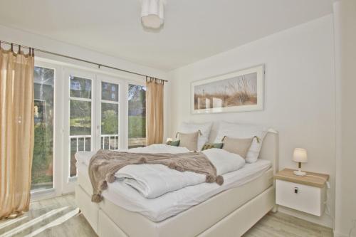 a white bedroom with a bed and a window at Ferienwohnung mit Balkon, Kamin und Sauna - Ferienresidenz Zwei Bodden FeWo 2-9 in Lietzow