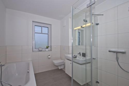 a white bathroom with a tub and a toilet and a sink at gemütliche Ferienwohnung mit Terrasse und Garten - Ferienhaus Zaunkönig FeWo EG in Groß Zicker