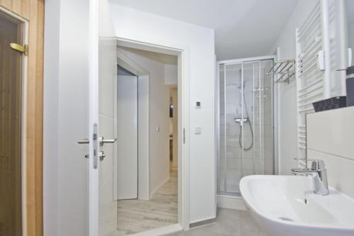 y baño blanco con lavabo y ducha. en Ferienwohnung mit Terrasse, Kamin, Sauna - Ferienresidenz Zwei Bodden FeWo 2-6, en Lietzow