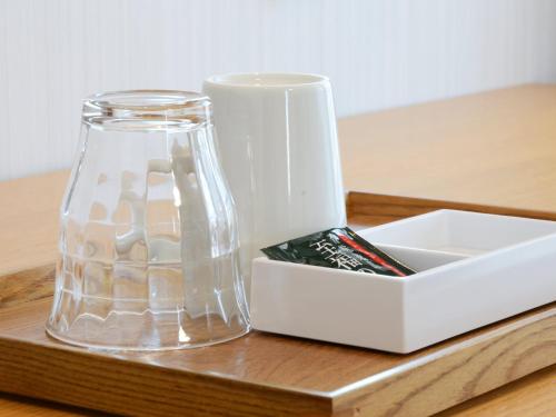a glass vase and a box on a wooden table at Hotel AreaOne Obihiro in Obihiro