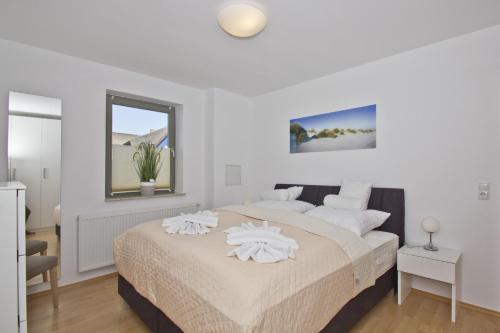 ein weißes Schlafzimmer mit einem großen Bett mit weißen Kissen in der Unterkunft Balkon mit Meerblick, ruhige Lage - Ferienhaus Distelfink FeWo 01 in Groß Zicker