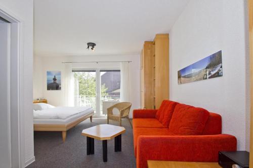 sala de estar con sofá rojo y cama en nur 100 m zum Strand, FeWo mit Balkon und Terrasse - App Eldena FeWo 04, en Lobbe