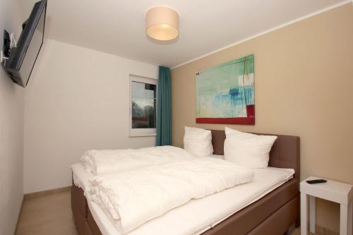 1 dormitorio con 1 cama con sábanas blancas en strandnahe FeWo mit Terrasse, gratis Nutzung vom AHOI Erlebnisbad und Sauna in Sellin - Rex Rugia FeWo 13-3, en Lobbe