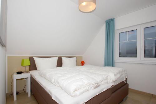 a bedroom with a large white bed with a window at strandnahe FeWo mit Balkon, gratis Nutzung vom AHOI Erlebnisbad und Sauna in Sellin - Rex Rugia FeWo 13-8 in Lobbe