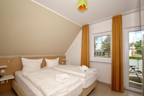ein Schlafzimmer mit einem Bett mit weißen Laken und einem Fenster in der Unterkunft strandnahe FeWo mit Balkon, gratis Nutzung vom AHOI Erlebnisbad und Sauna in Sellin - Rex Rugia FeWo 30-8 in Lobbe
