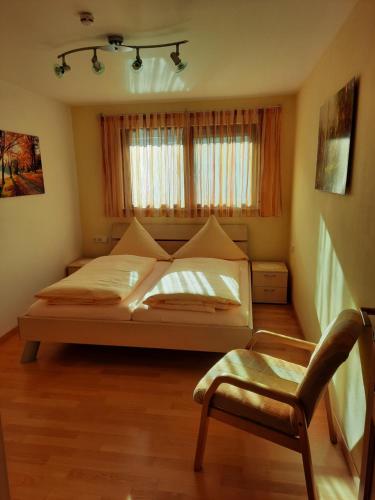 a bedroom with a bed and a chair and a window at Ferienwohnung Sprauer in Baiersbronn