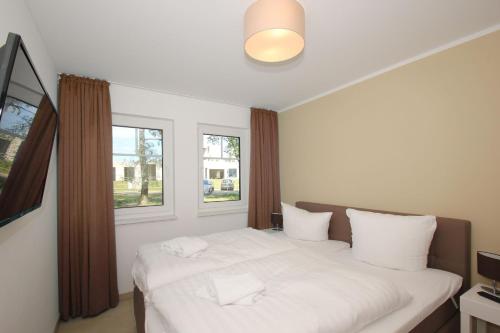a white bed in a room with two windows at strandnahe FeWo mit Terrasse, gratis Nutzung vom AHOI Erlebnisbad und Sauna in Sellin - Rex Rugia FeWo 14-1 in Lobbe