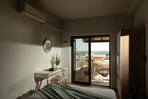 a bedroom with a bed and a desk and a balcony at Arolithos Home in Almirida