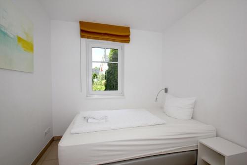 ein weißes Schlafzimmer mit einem Bett und einem Fenster in der Unterkunft strandnahe FeWo mit Terrasse, gratis Nutzung vom AHOI Erlebnisbad und Sauna in Sellin - Rex Rugia FeWo 29-3 in Lobbe