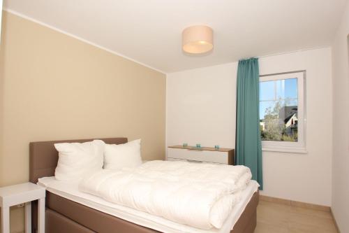 a bedroom with a white bed and a window at strandnahe FeWo mit Balkon, gratis Nutzung vom AHOI Erlebnisbad und Sauna in Sellin - Rex Rugia FeWo 13-5 in Lobbe
